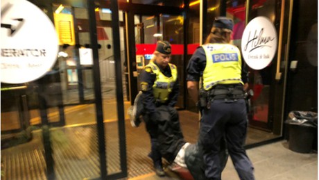 Cảnh sát Thuỵ Điển khiêng du khách ra khỏi khách sạn vì nghi họ là dân tị nạn. Nguồn: CGTN..