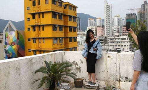 Các du khách trẻ sở dĩ thích leo lên nóc nhà ở Hong Kong chụp ảnh vì lấy cảm hứng từ họa sĩ nổi tiếng người Tây Ban Nha, Okuda San Miguel. Miguel từng chụp các bức ảnh trên tòa nhà cao tầng ở phố Wong Chuk. Ảnh: SCMP.