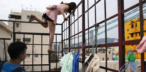 Nhiều du khách bất chấp nguy hiểm, đã trèo rào để được lên phần sân thượng của tòa nhà cao tầng chụp ảnh ở Hong Kong. Ảnh: SCMP.
