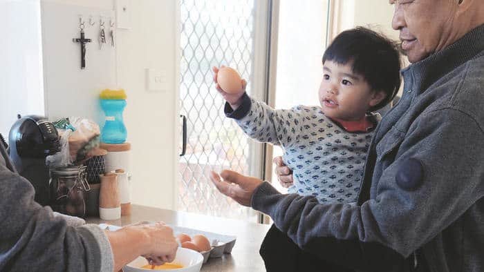 grandparents are whisking an egg and preparing breakfast with toddler