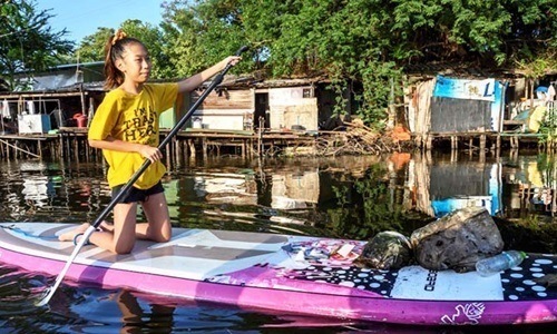 Lilly tự chèo thuyền gom rác trên một con kênh ô nhiễm ở Bangkok, Thái Lan. Ảnh: AFP.