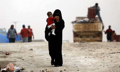 Một phụ nữ bế con tại trại tị nạn Ain Issa, Syria. Ảnh: AFP.