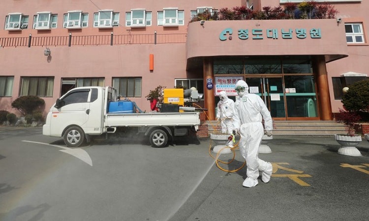 Nhân viên y tế mặc đồ bảo hộ phun hóa chất tẩy trùng trước bệnh viện đang điều trị cho 16 bệnh nhân nhiễm nCoV tại thành phố Daegu, Hàn Quốc ngày 21/2. Ảnh: AFP.