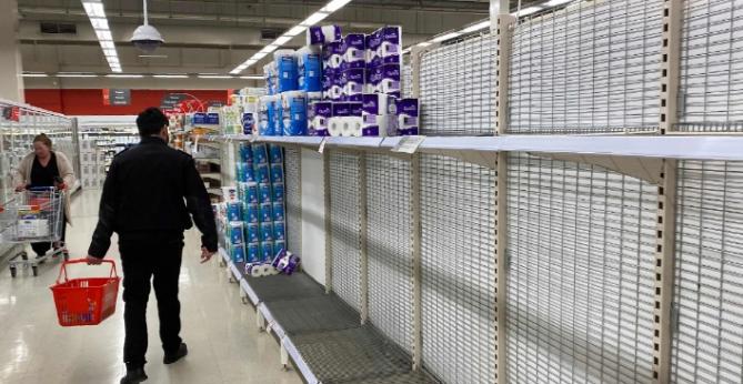 Một người mua sắm đi ngang qua các kệ giấy vệ sinh gần như trống rỗng tại một siêu thị ở Melbourne. Ảnh: AFP