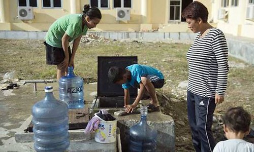 Một cậu bé (giữa) đang cố lấy nước sạch từ bể ngầm trong một trung tâm sơ tán tại Palu. Ảnh: AFP.