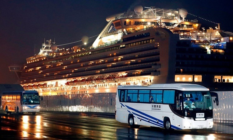 Xe buýt đưa các công dân Mỹ từ cảng Yokohama tới sân bay Haneda ở Tokyo để về nước. Ảnh: AP.
