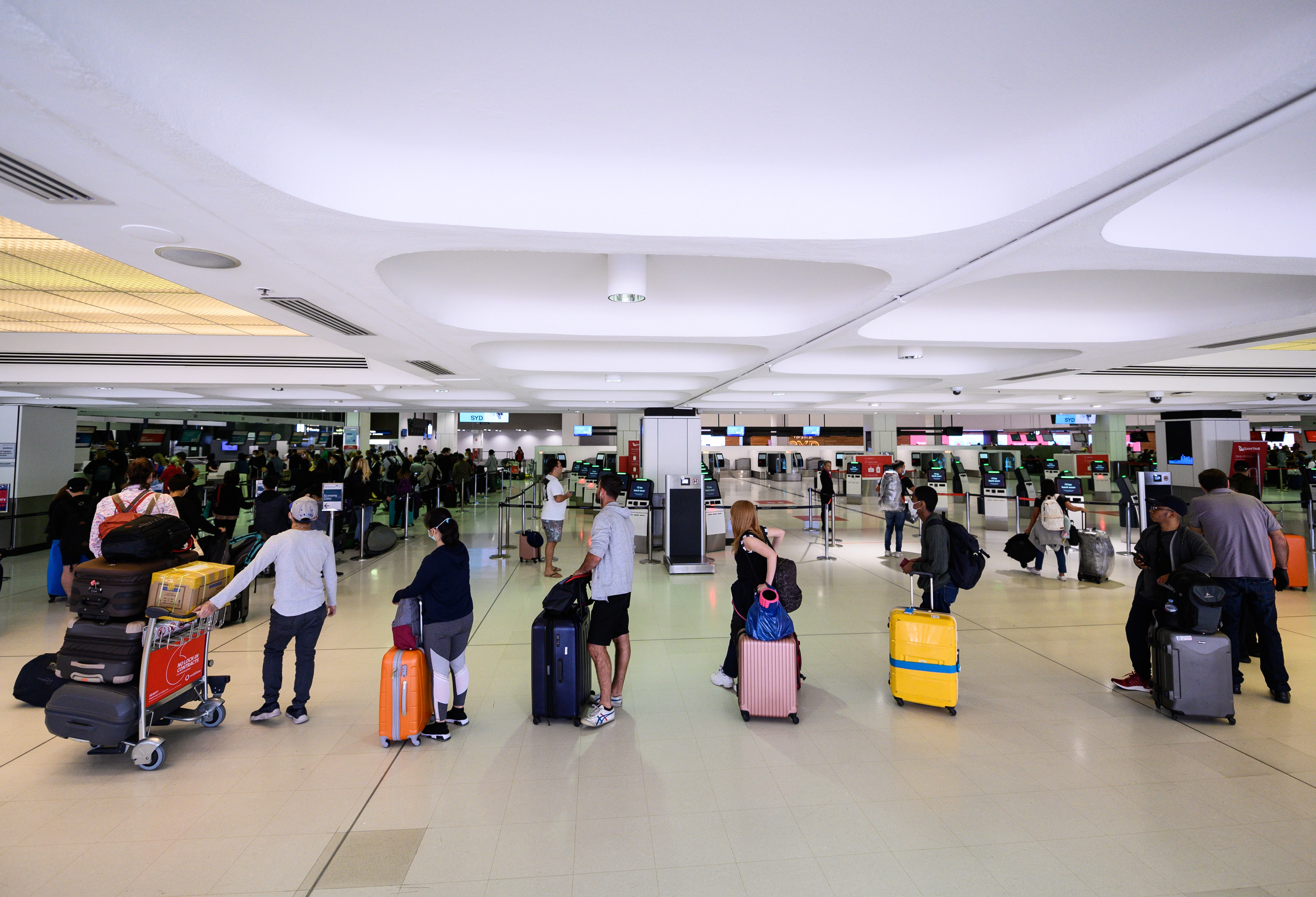 Travellers adhere to social distancing rules as they check in for their flights at Sydney International Airport in March 2020.