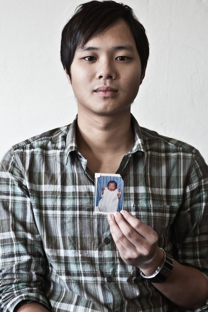 Michael Trương holding up the first photo ever taken of him when he was born in 1983